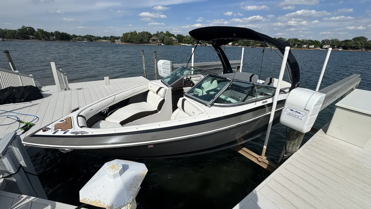 Spotless ski boat on its lift at a Lake Norman dock, with lake houses across the water
